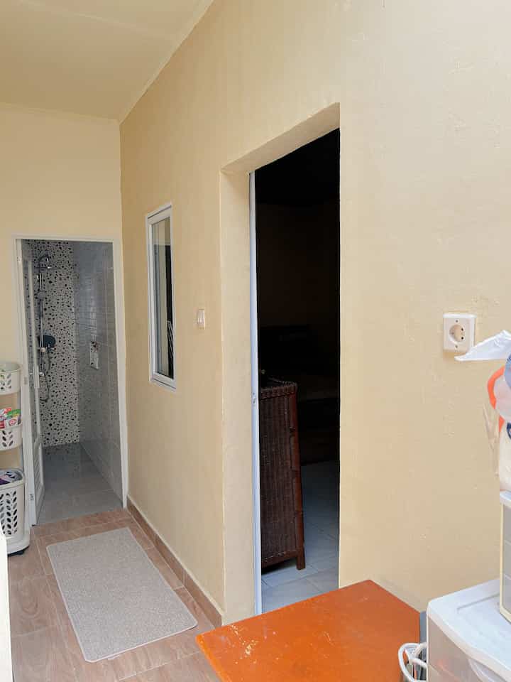 Beige-toned narrow corridor laundry space featuring laundry baskets and bath mat on the left with practical layout