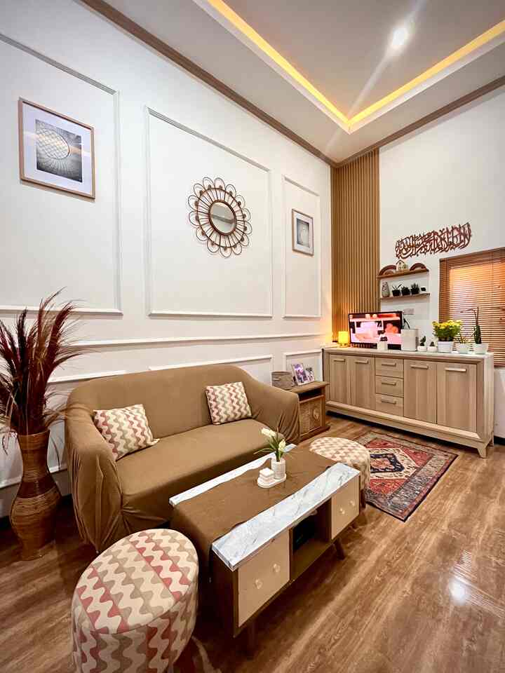 A cozy living room with warm wood tones and beige sofa, featuring a round mirror and framed art on the wall