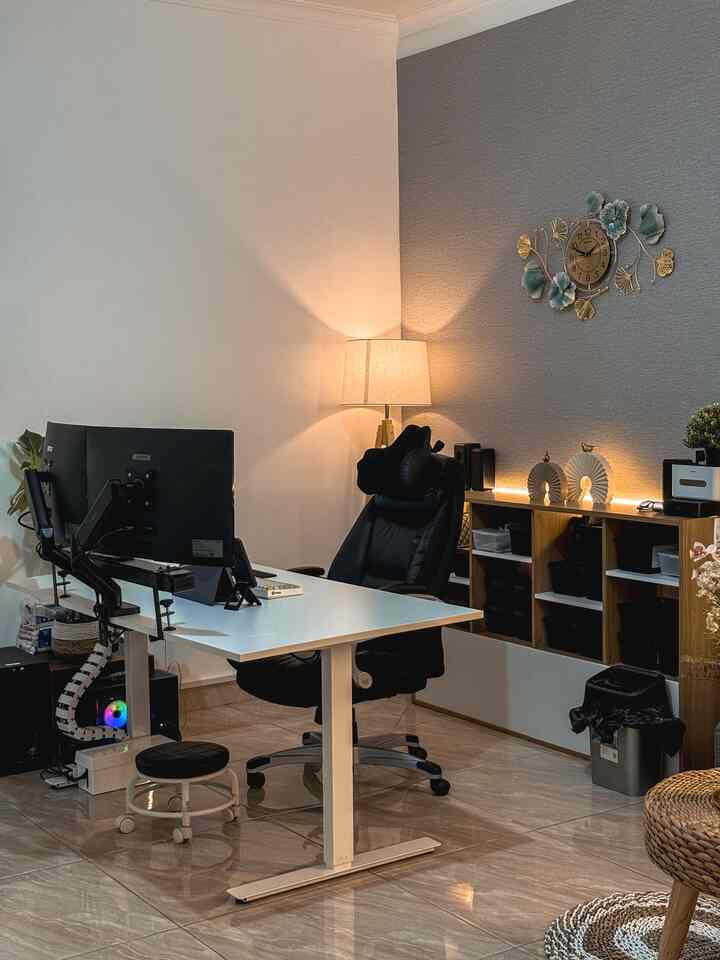 White and wood-toned home office featuring a black office chair and desk with a modern and cozy remote work atmosphere