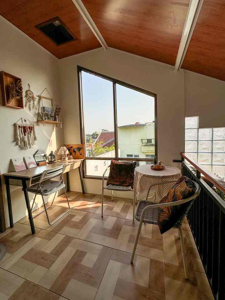 Brown and beige toned balcony space featuring a desk and dining chairs bathed in natural light