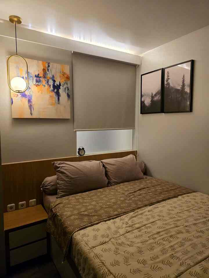 Beige-toned small bedroom featuring bed, nightstand, modern wall art, and blackout curtain creating a cozy atmosphere