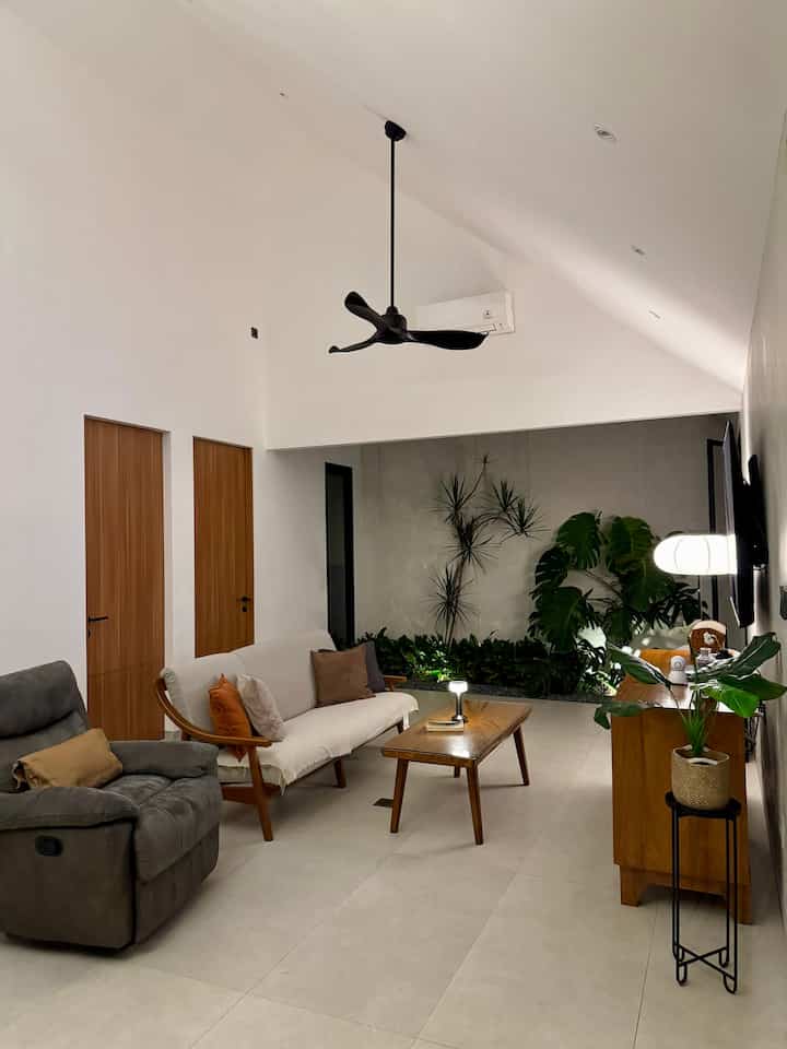 Natural toned living room space featuring wooden furniture and plants with a modern, cozy atmosphere