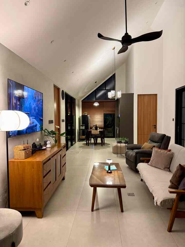 Warm wood tones and modern furniture in a spacious living room with a prominent slanted ceiling and cozy lighting