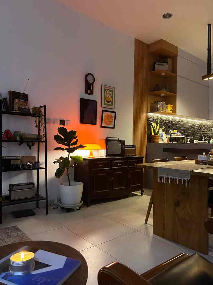 Natural space combining kitchen and living room featuring warm orange lighting and wood tone furniture
