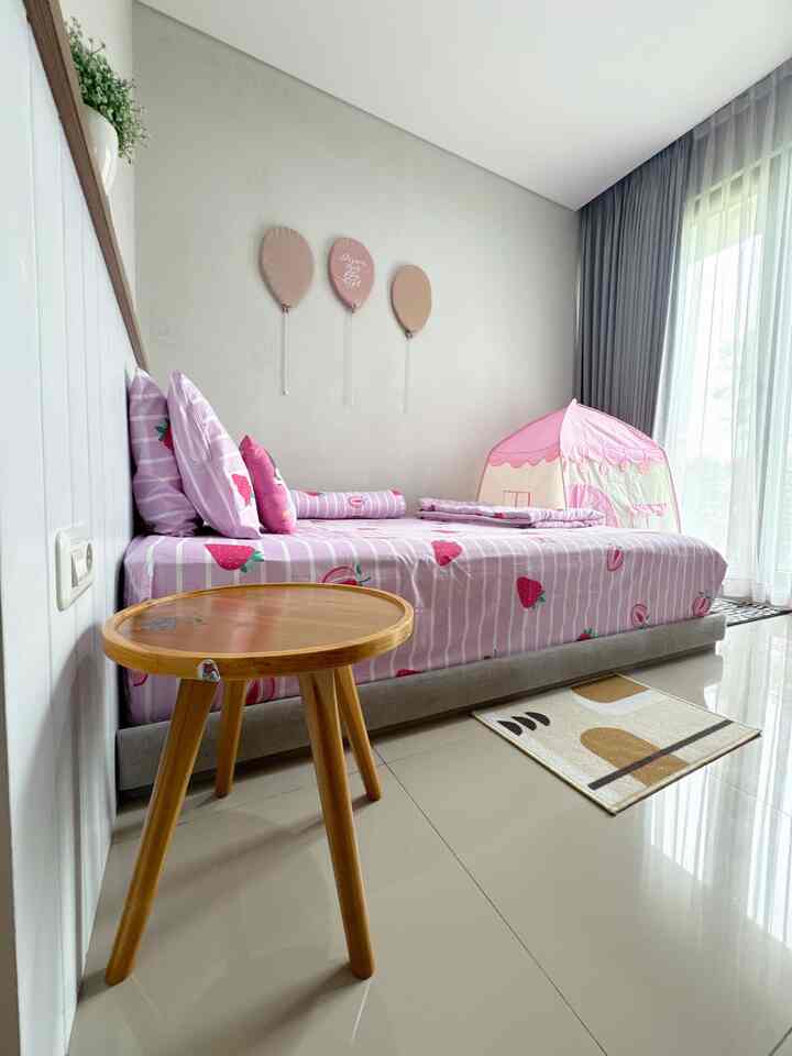 Pink-toned kids' bedroom featuring strawberry-patterned bedding and a small play tent, creating a cozy atmosphere