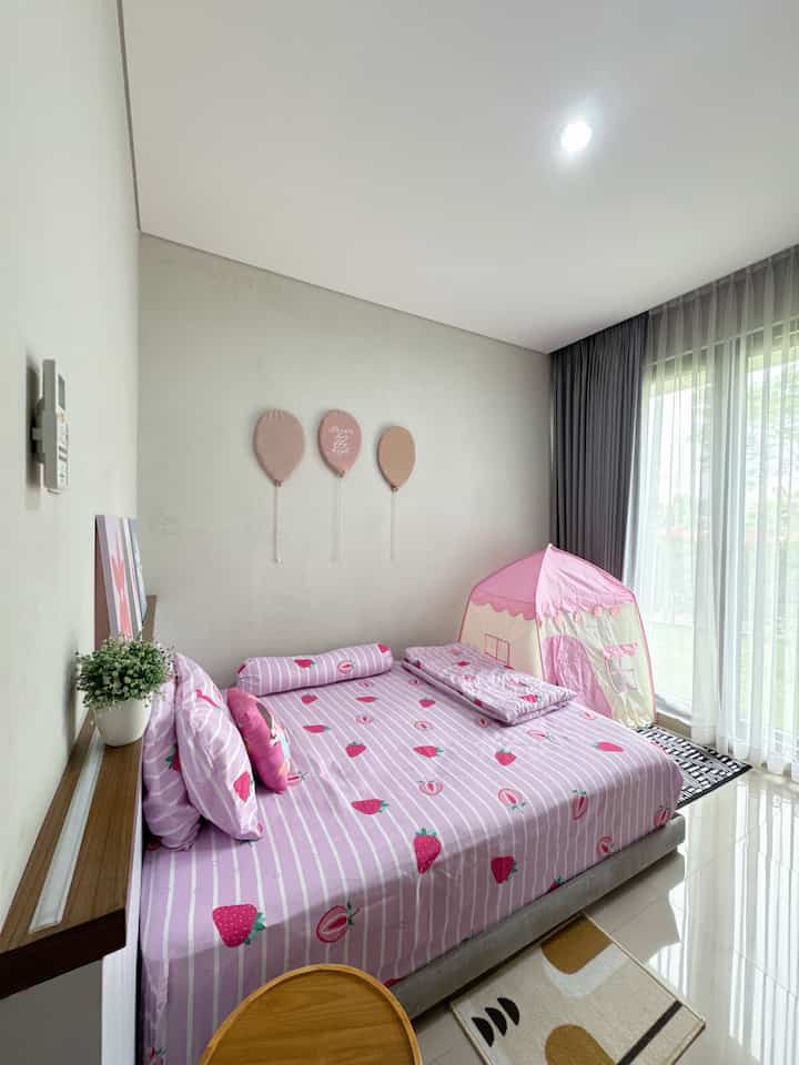 Pink and white toned kids' room featuring a pink tent, cute balloon wall art and a small wooden table with a cozy atmosphere