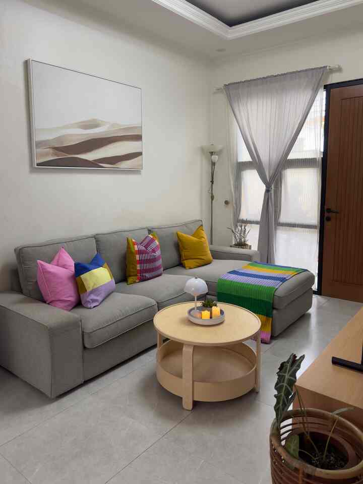 Gray-toned living room featuring a gray sectional sofa and beige round coffee table with a cozy, neat atmosphere