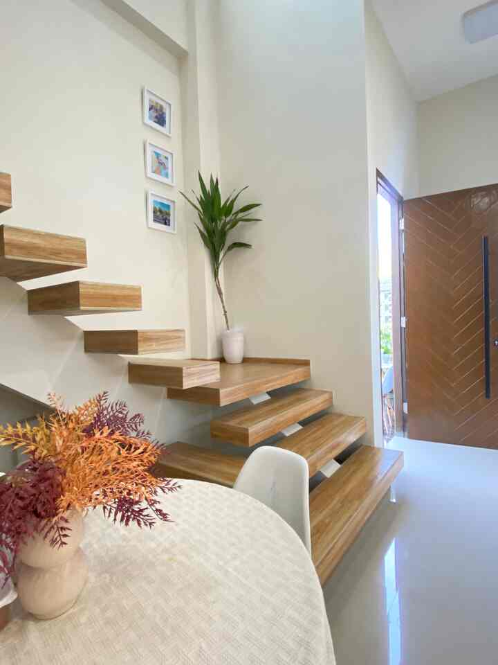 Natural tone living room featuring wooden floating stairs and dining table with warm atmosphere