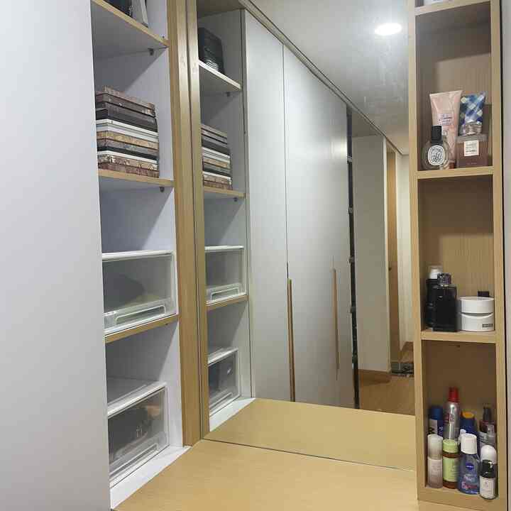 White walls and built-in closet in a narrow entrance featuring wood-tone vanity and storage cabinets in a functional setup
