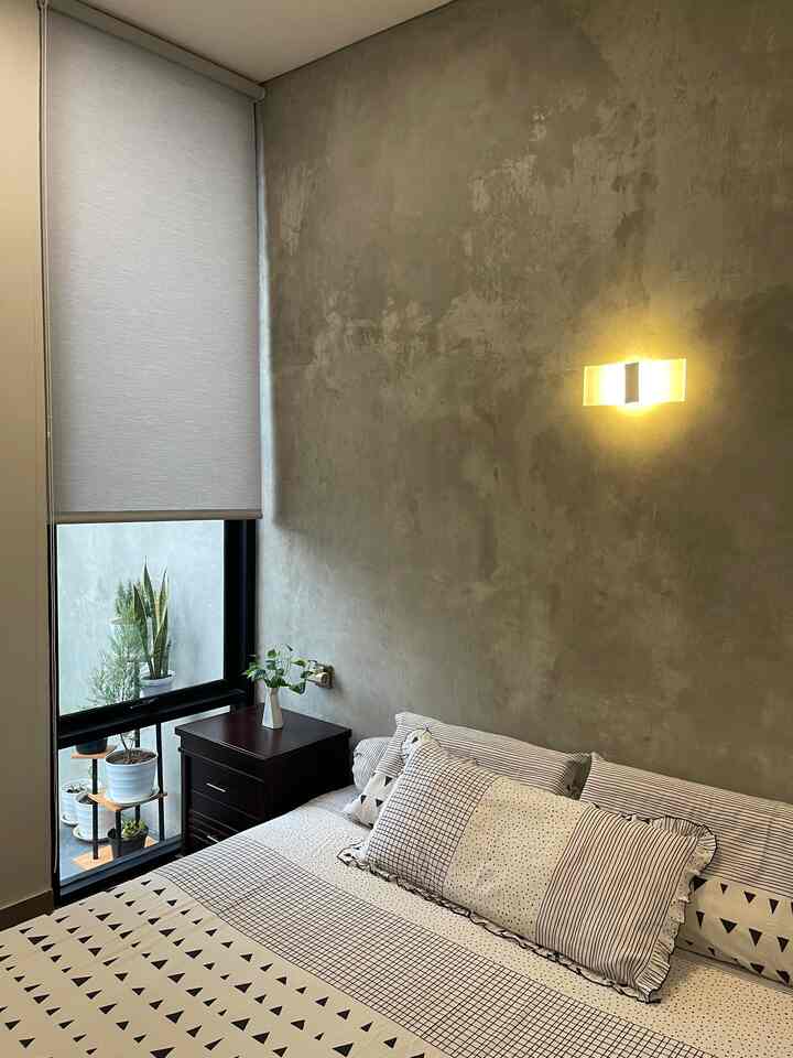 Gray-toned bedroom featuring blackout curtain, wooden nightstand, and cozy bedding in a minimalistic space