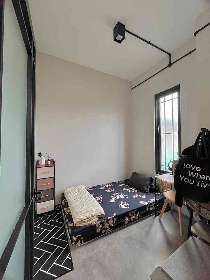 A bright white and natural gray toned bedroom featuring floral bedding and a small desk in a neat, minimal space