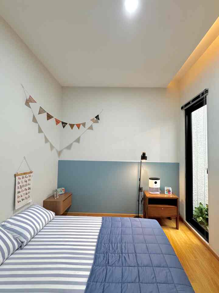 Blue and white toned kids' room featuring wooden floor, garland decoration, and a cozy bright bedroom space