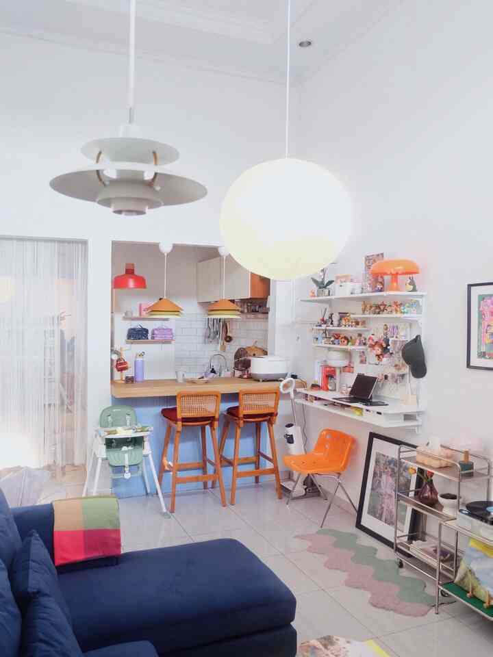 Bright white and natural-toned living room and kitchen featuring a blue sofa and orange pendant lamps in a modern setting