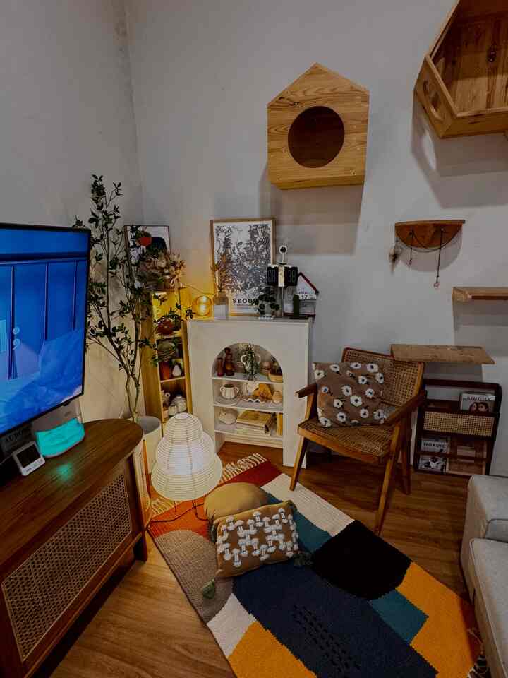 Cozy living room with natural wood tones featuring a wooden dog house, colorful rug and cushions creating a warm atmosphere