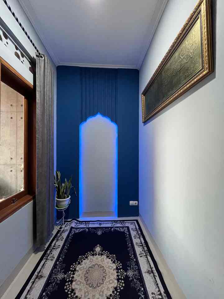 Sebetulnya ini adalah area tersembunyi di rumah navy ini. Awalnya area ini akan dijadikan ruang kerja namun jadi berubah fungsi jadi mushola yang terinpirasi saat ada tamu berkunjung ke rumah lalu ikut sholat disini. Karena bingung tidak ada area shalat untuk tamu dan keluarga kami sendiri selain di kamar akhirnya kami membuat mushola ini di area masuk rumh yang di sekat oleh partisi. 
Uniknya ruangan ini adalah Mihrabnya yang suami buat dari DIY barang sisa material bahan bangunan yang ada. Bahannya antara lain terdiri dari gypsum sisa dari flavon dan PVC alderon sisa dari kanopi. Kami hanya membeli besi hollow untuk rangkanya serta mengecat dengan warna khas dari Nippon kode Bachelor, tak lupa kami tambahkan LED Strip untuk membuat suasana semakin hangat dan estetik. 
Satu lagi kami juga memasang kaligrafi, menyimpan tanaman asli di sudut ruangan serta karpet supaya beribabdah dengan tenang dan nyaman. 
Semoga menginspirasi yaa🤗💙
#musholaminimalis
#DIY
#DIYMihrab
#KaligrafiJumbo
#KarpetEropa
#MihrabMushola
#RuangMinimalis
