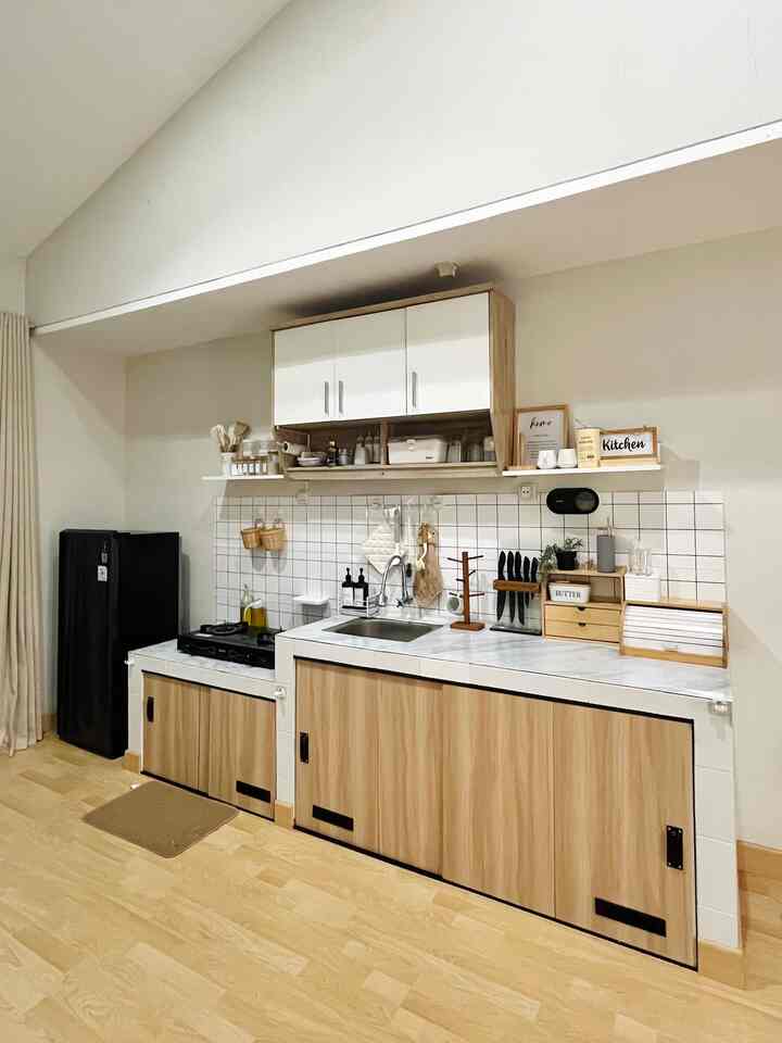 Minimal compact kitchen space featuring white and wood tones, clean storage solutions, and tiled backsplash creating a tidy atmosphere