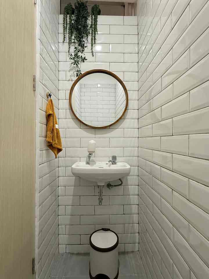 Powderroom ini ruangan paling sempit di rumah, tapi jadi yang paling diperhatiin.

Ukuran lebarnya cuma 80 cm, tapi justru jadi salah satu spot yang paling sering dikomentarin tamu. Sempit, iya. Tapi tetap bisa nyaman dan enak dilihat? Bisa banget.

Tips dekorasi ruang mungil versiku:

✴️Gunakan warna terang dan ubin motif horizontal supaya kesan ruang jadi lebih luas.

✴️Cermin bulat jadi focal point, selain bikin ilusi ruang lebih terbuka tampilannya yang minimalis dengan frame kayu juga tetap estetis.

✴️Kasih aksen warna kontras dari handuk dan hijau-hijauan dari tanaman agar ruangan jari gak monoton.

✴️Tanaman gantung di atas cermin bantu tarik perhatian ke atas, jadi ruang terasa lebih “tinggi”.

✴️Barang fungsional = dekorasi. Bahkan tempat sampah pun dipilih yang senada biar tetap rapi dilihat.

Kadang, ruang terkecil justru jadi bukti kalau detail itu penting.
Dan percaya deh, setiap sudut rumah bisa ‘hidup’ kalau ditata dengan tepat.

#PowderRoomGoals #DekorasiRuangMungil #KamarMandiEstetik #HomeInspo #RumahNyaman #CerminKayu #ArtificialPlants #KeramikSubway #WoodenHook