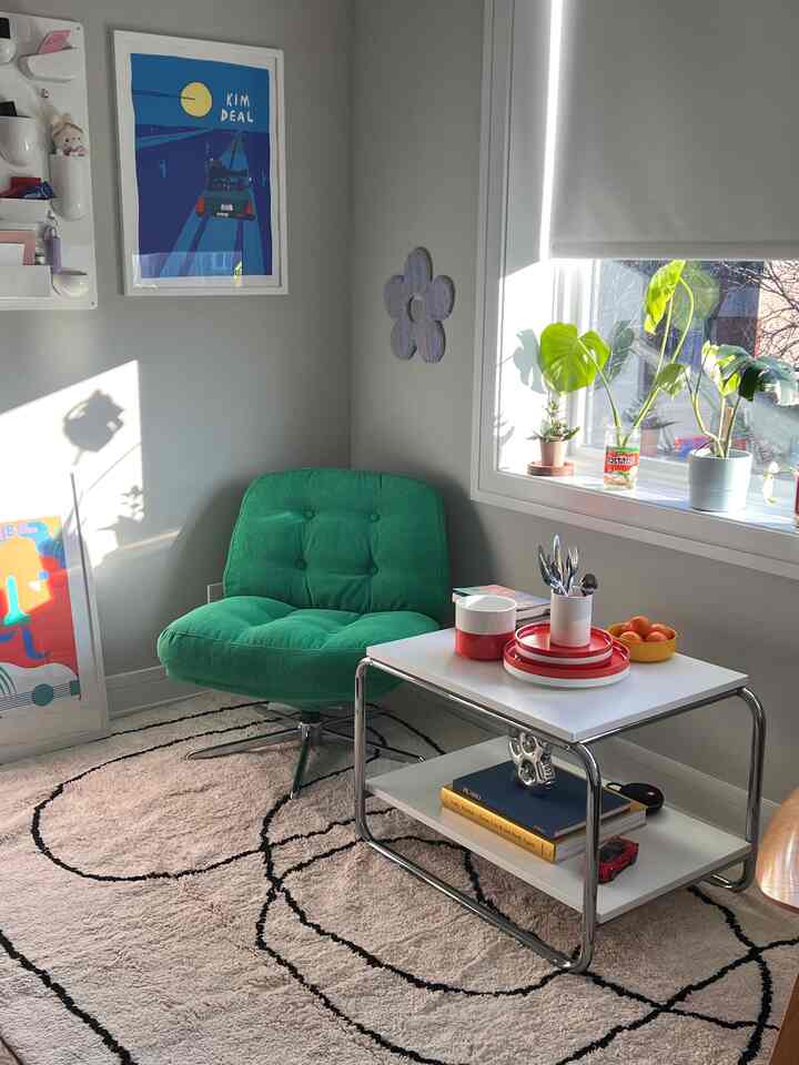 Cozy living room corner with soft natural light, featuring a green armchair, side table, and decorative plants