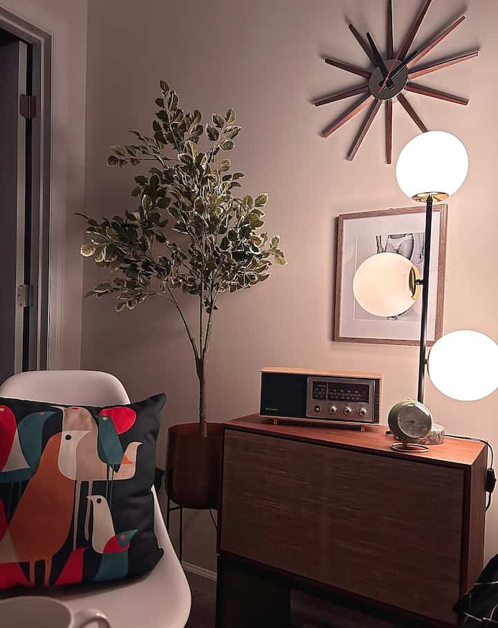 Beige-toned bedroom corner featuring Mid-Century Modern wooden sideboard and bird-patterned cushion in cozy setting