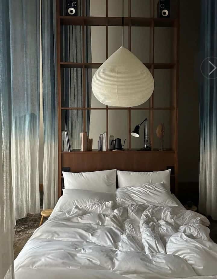 Minimal and calm bedroom featuring a white bed and warm wood tones, hotel-like sleek interior