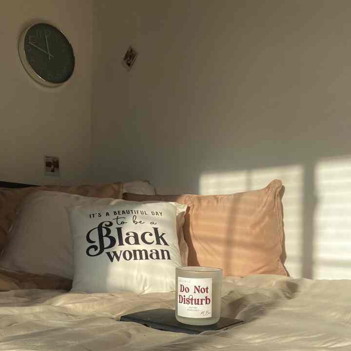 Soft white and beige bedroom featuring tidy bedding and a candle, creating a peaceful ambiance