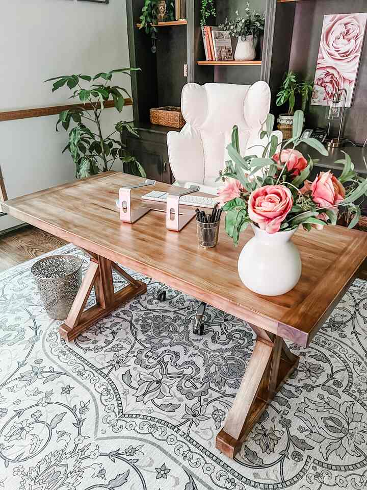 Natural wood-toned home office space featuring a white office chair and a vase of flowers on the desk