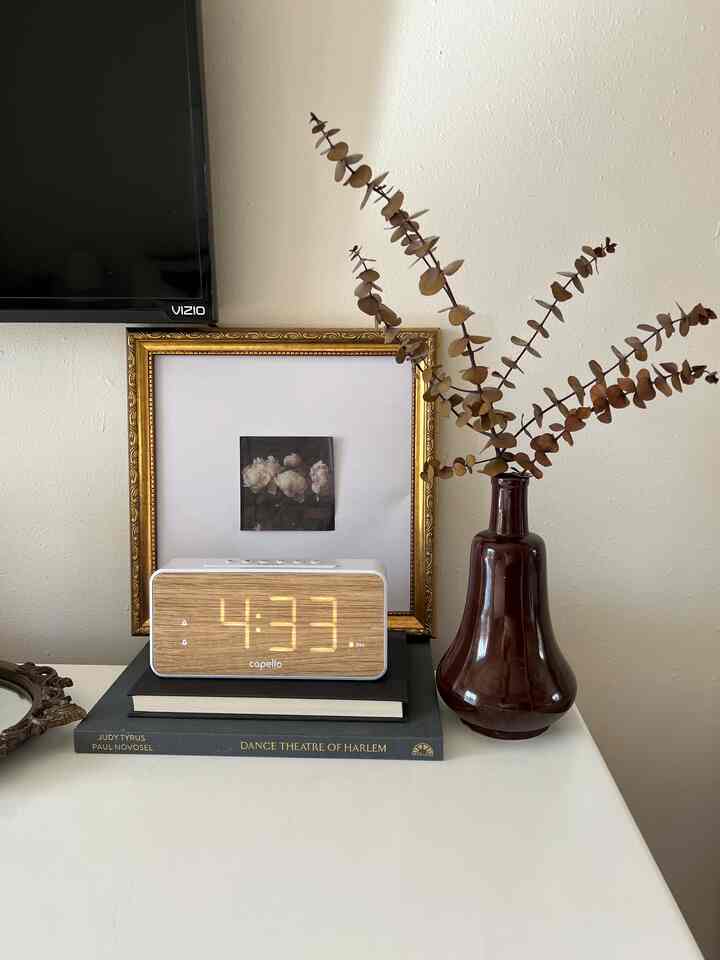 Brown-toned bedroom featuring a digital alarm clock and a gold picture frame, creating a cozy atmosphere