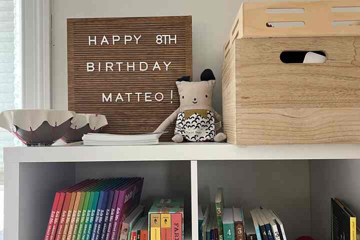 Wood tone and white kids' room bookshelf featuring toy storage and colorful children's books in a cozy setting