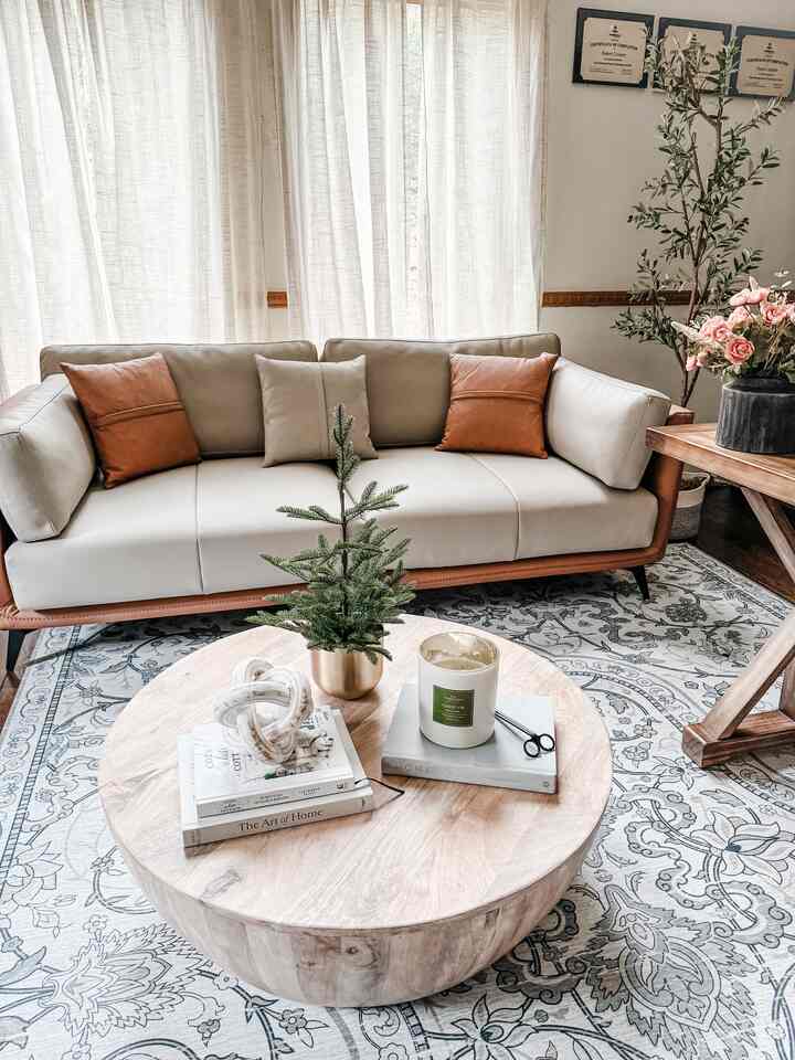 Natural modern home office and living room featuring a beige leather sofa and round wooden coffee table with a cozy atmosphere
