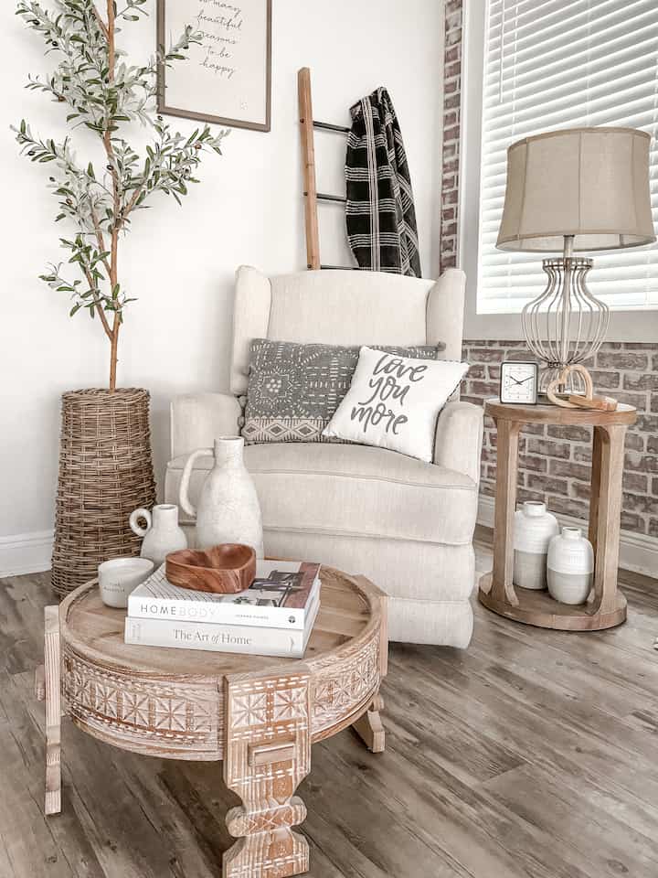 Warm beige and natural wood-tone living room corner featuring a comfortable armchair and wooden tables creating a cozy atmosphere