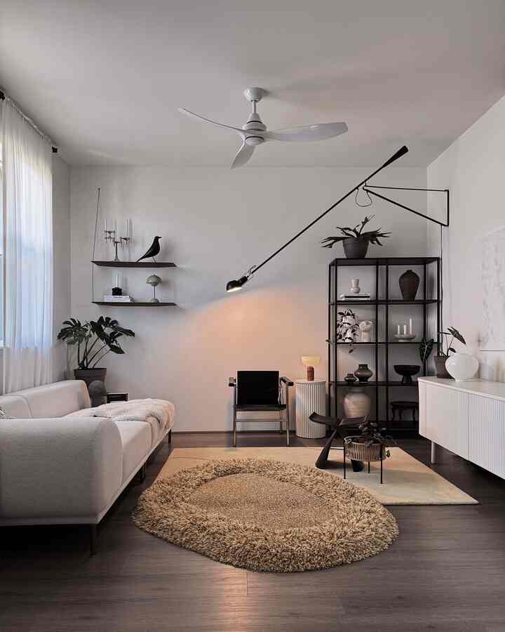 White and brown toned Nordic living room featuring sofa, rugs, shelves, and floor lamp with a cozy atmosphere