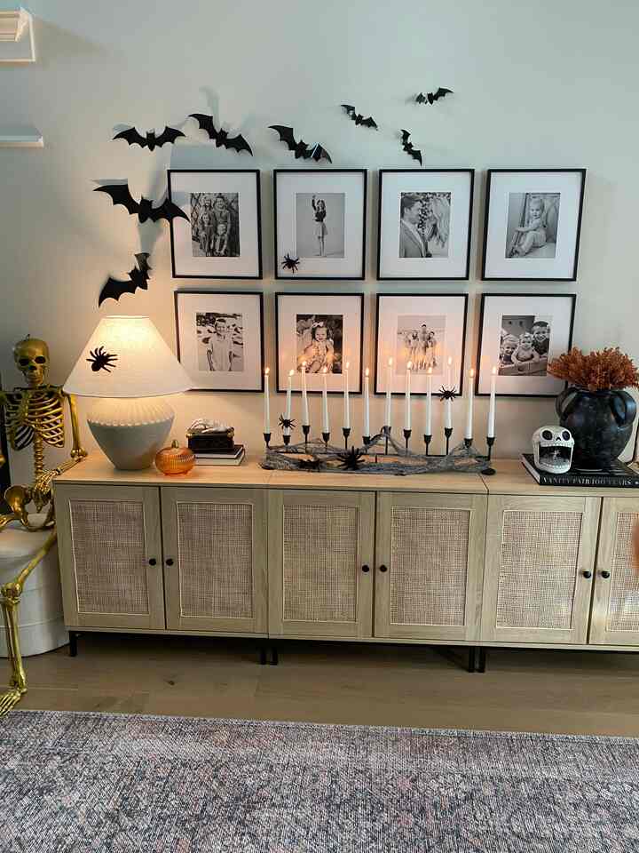 Entrance space featuring brown wood tone console with gold skeleton and Halloween decor, black-framed photos on wall