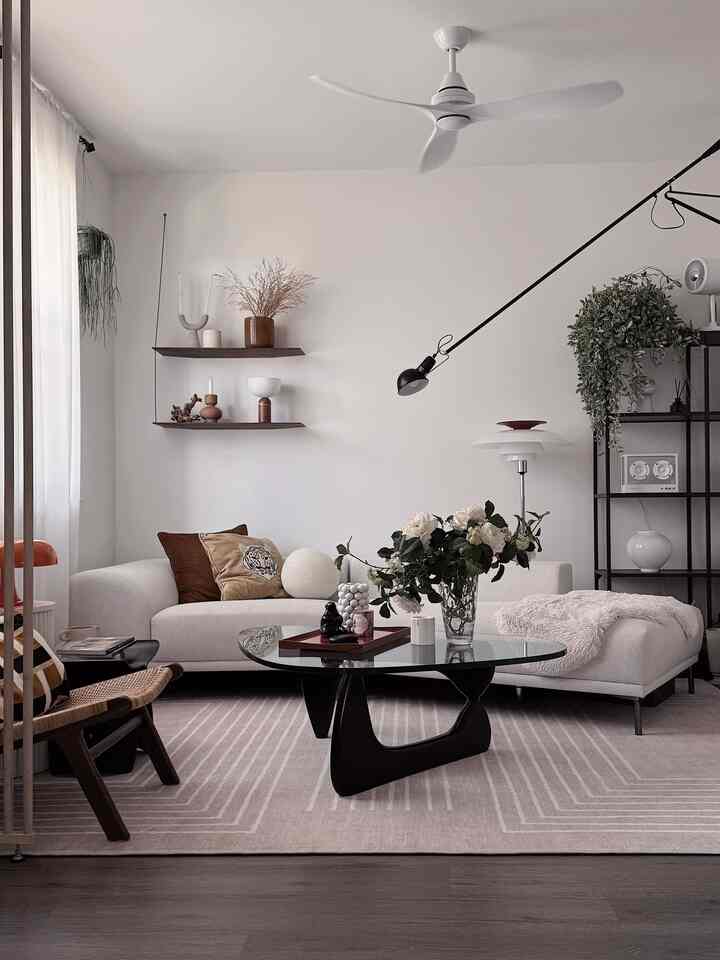 White and brown toned mid-century modern living room featuring sectional sofa and glass coffee table with cozy atmosphere
