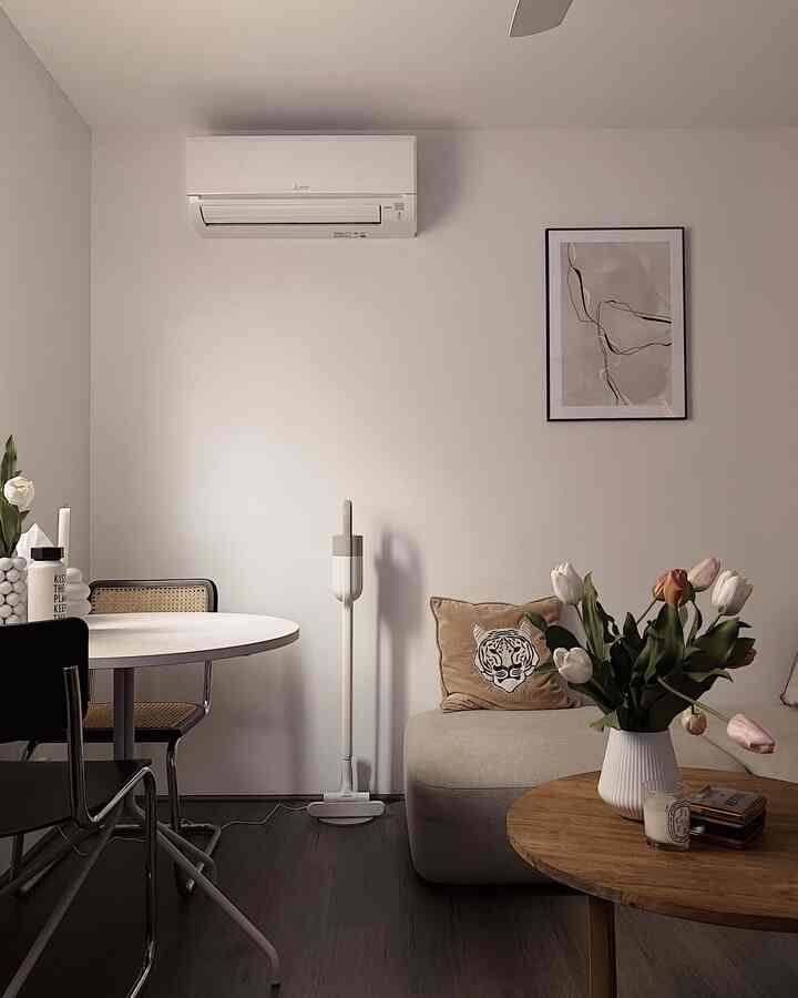 Natural and simple living room with white walls, beige sofa, and wooden round table featuring a vase of flowers