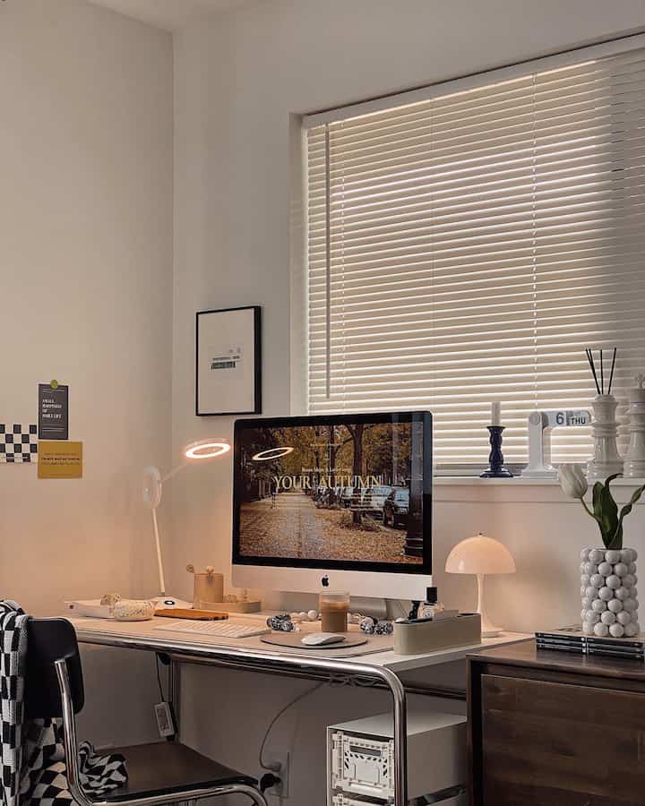 White and brown toned home office space featuring iMac and table lamp with a minimalistic, natural desk setup