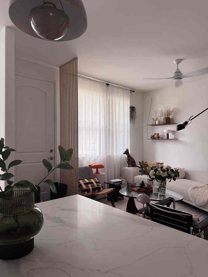 White and wood tone living room with natural light from windows, featuring a dog sitting by the window, cozy natural interior
