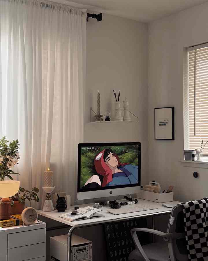 Bright white-toned home office featuring a tidy desk with iMac, shelf, and candles creating a modern workspace