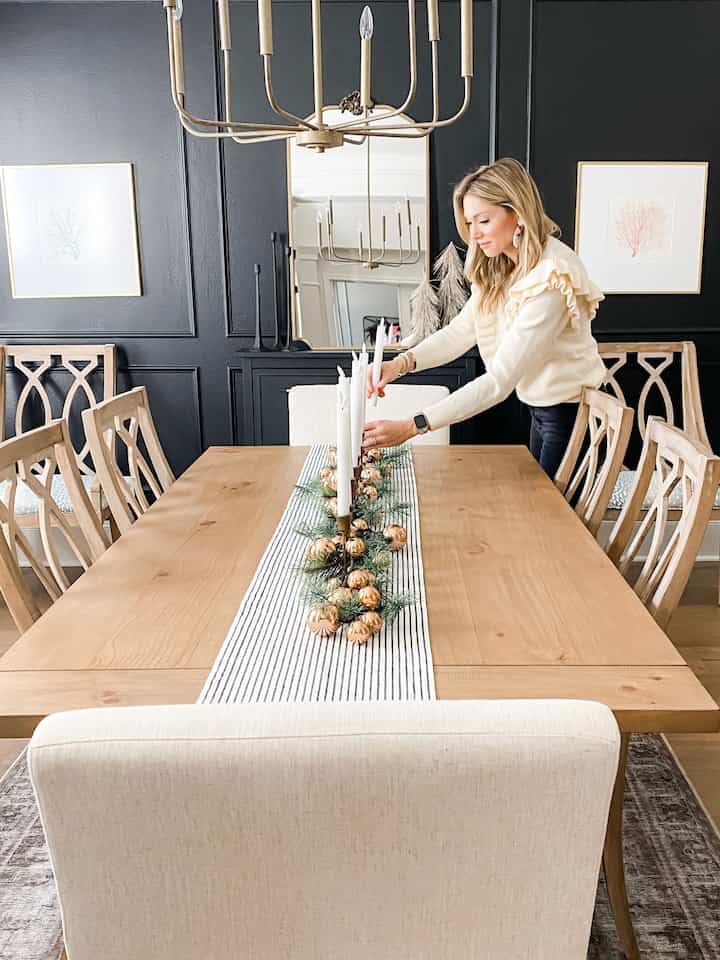 Natural-tone dining room featuring a wooden dining table with candles and gold ornament garland creating a cozy atmosphere