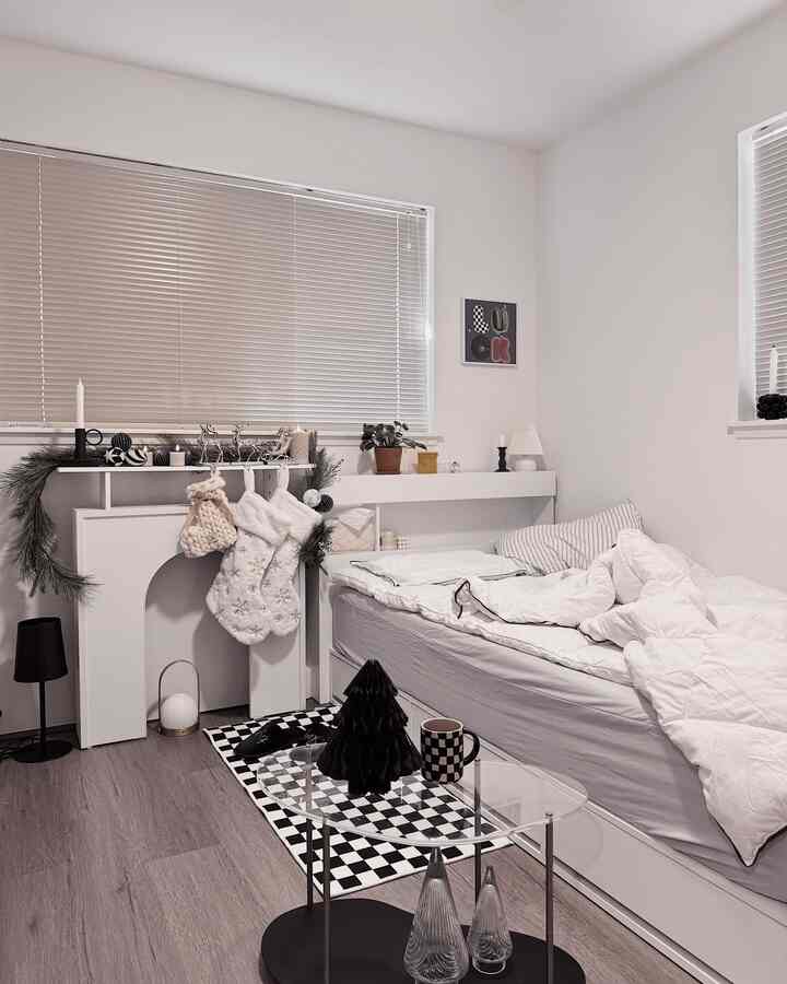White and black toned kids' room with Christmas decorations, featuring a bed and side table in a simple modern space
