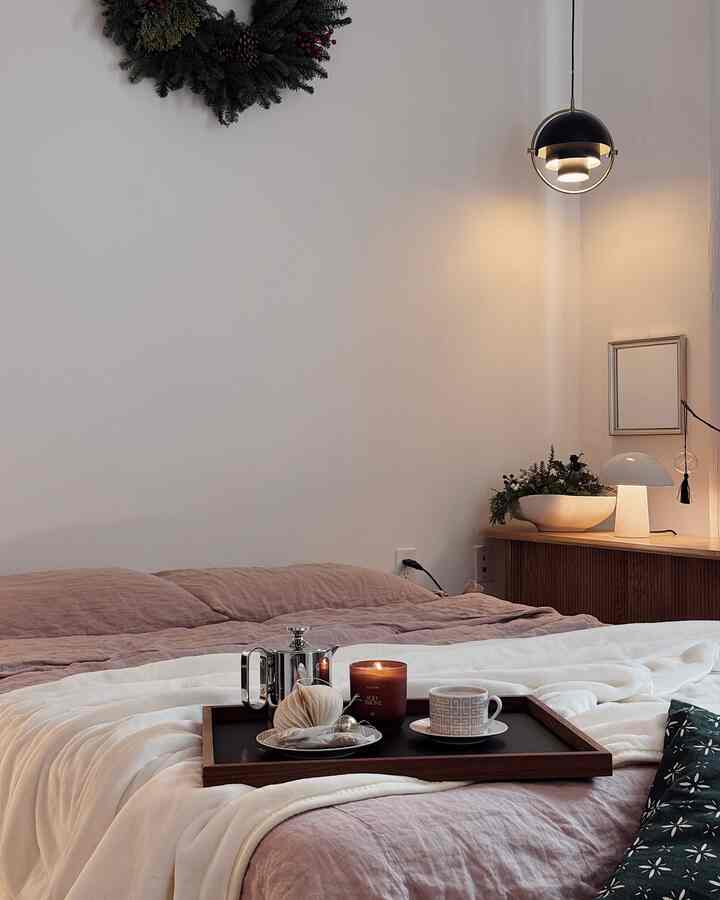 White and brown toned bedroom featuring cozy bedding, tray with candle, and warm ambient lighting