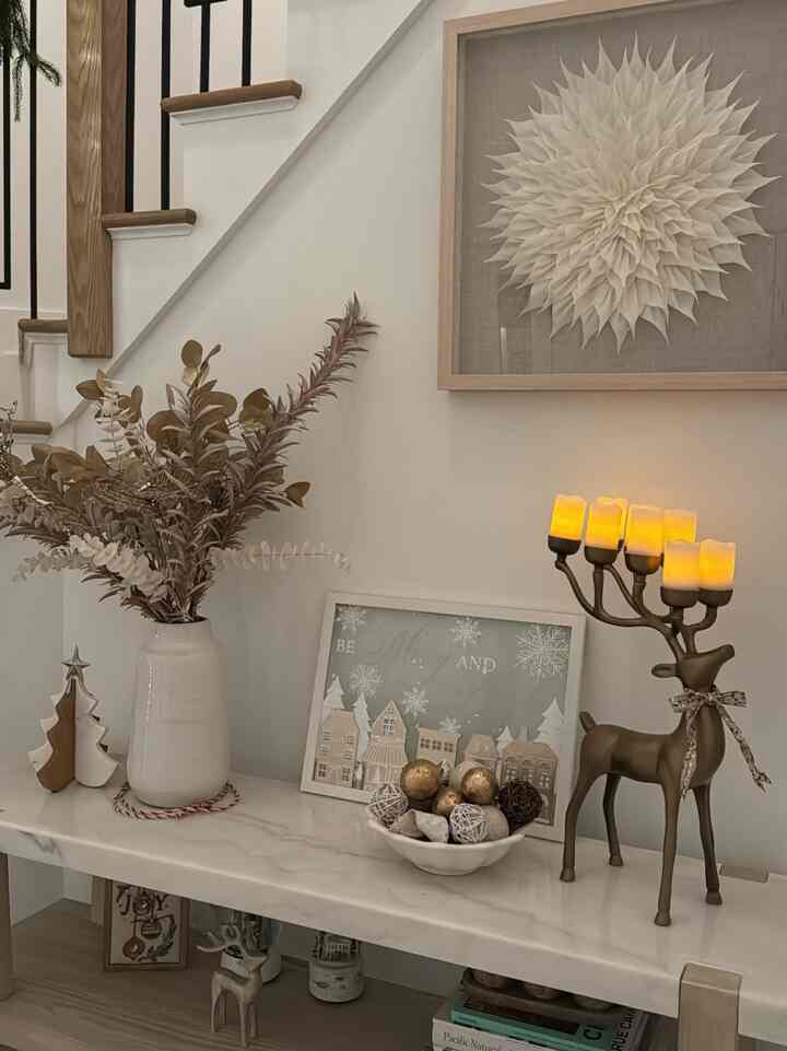 Natural modern living room with white background, dried plants, gold decorations displayed on console table under staircase