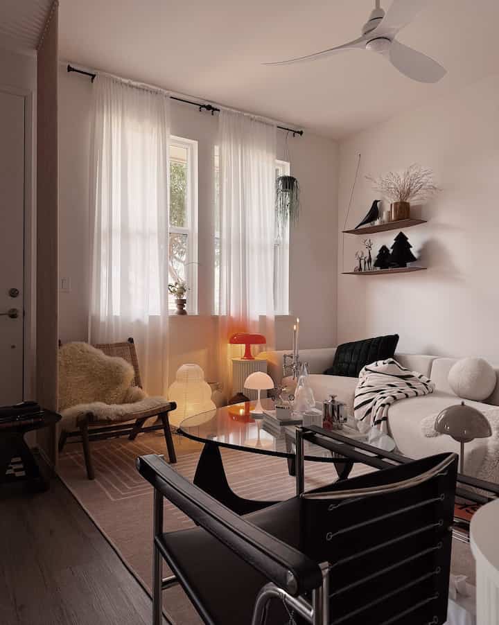 A soft white and warm brown toned living room featuring mid-century modern sofa and lamps creating a cozy atmosphere