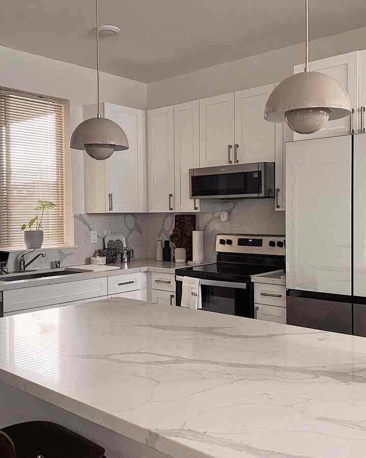 White and beige toned kitchen featuring beige pendant lights and blinds with a modern atmosphere