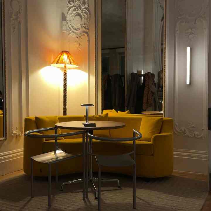 Yellow sofa and chrome-accented chairs in an Art Deco dining room with warm lighting and elegant wall moldings