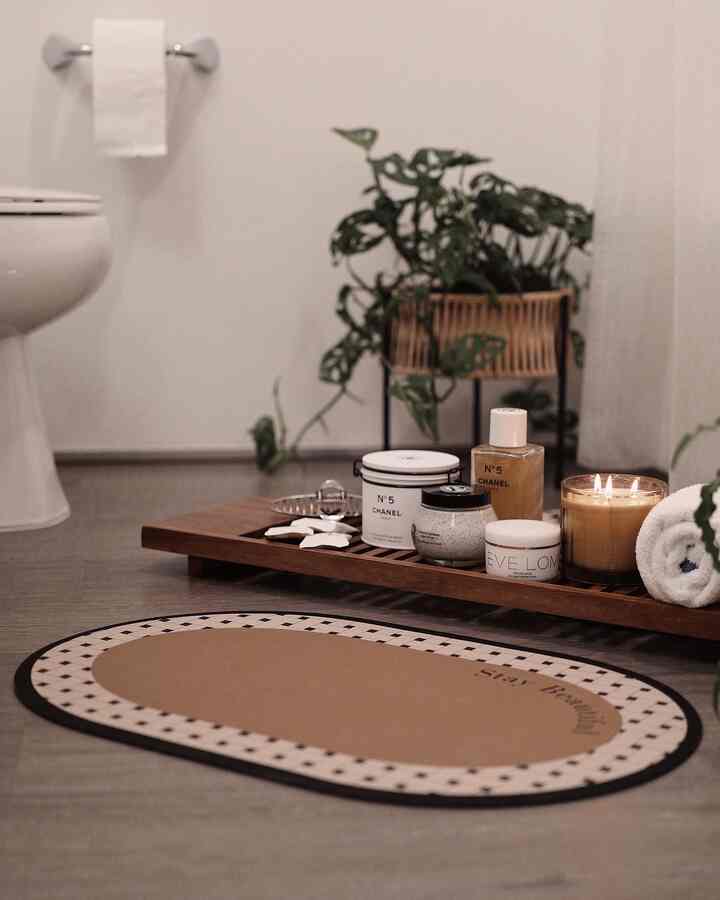 White and brown toned bathroom featuring an acacia wood tray, plants, and candles for a relaxing bath time atmosphere