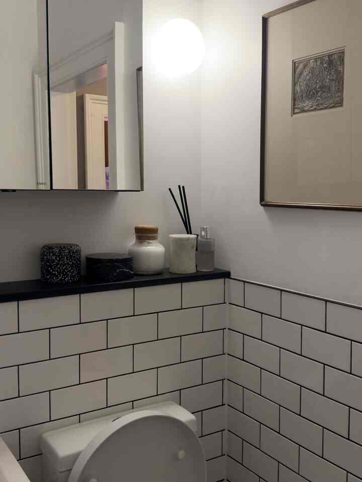Modern bathroom with white tiled walls and mirror, featuring clean decor elements and soft lighting ambience