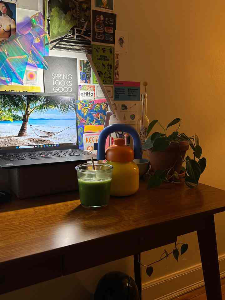 A warm-toned home office with a brown wooden desk featuring a laptop, desk lamp, and plant creating a cozy atmosphere.