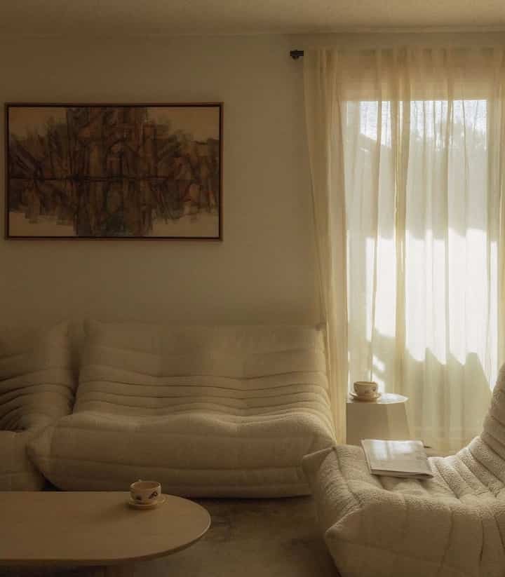 Beige-toned living room featuring soft beige sofas, wooden coffee table, and sheer curtains creating a peaceful Japandi atmosphere