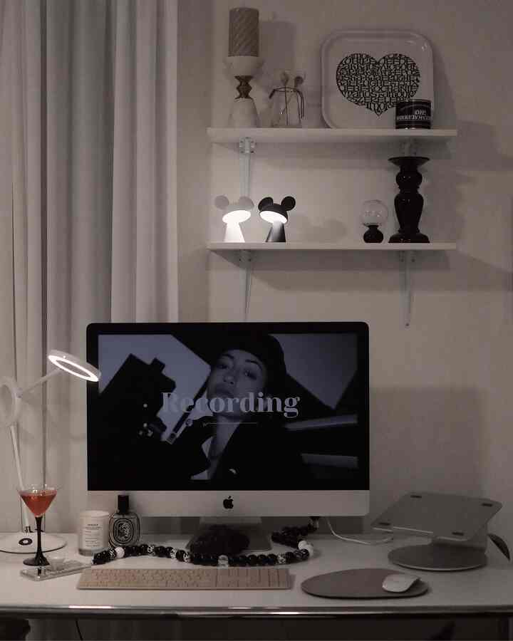 White-toned home office space featuring central desk with iMac and desk lamp, simple and monotone atmosphere