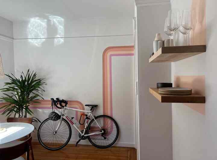 White-walled dining room with wood tone floor, maple floating shelves, and round dining table